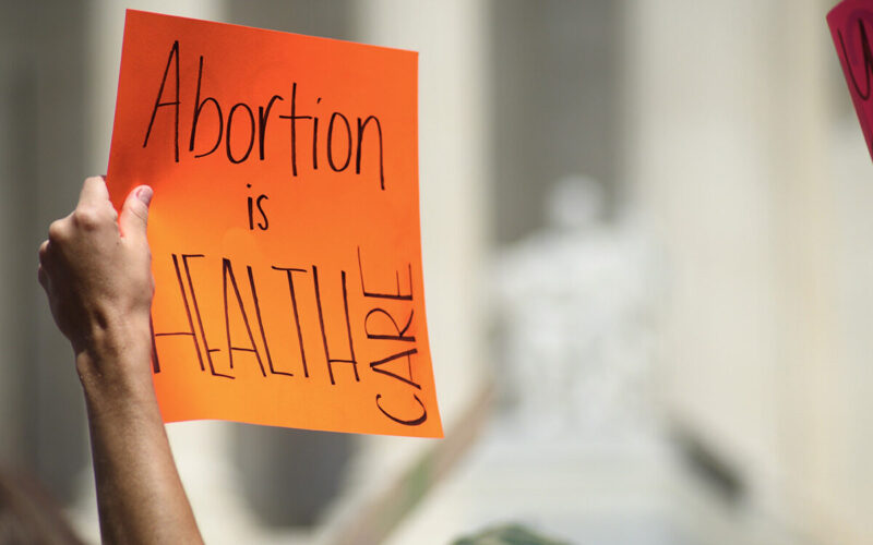 Photo Of A Hand Holding A Sign Which Reads "Abortion Is HEALTH CARE"