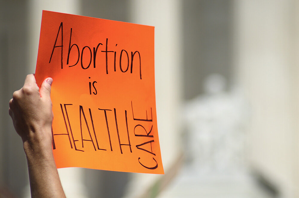 Hand holding sign which reads, "Abortion is Health Care."